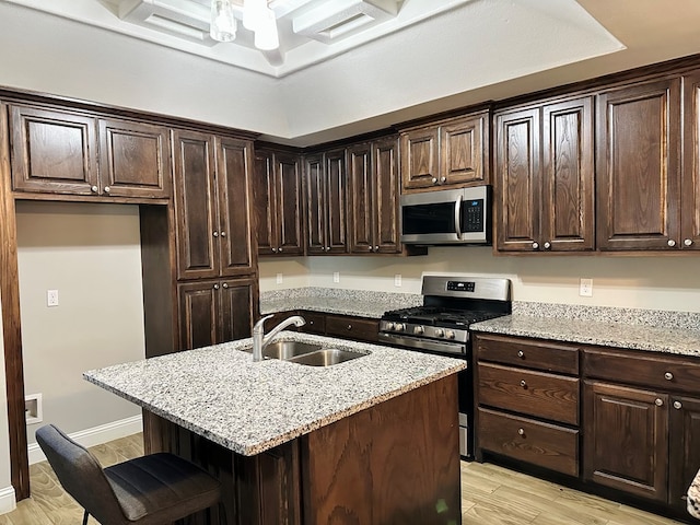 kitchen featuring a kitchen island with sink, light stone countertops, sink, and appliances with stainless steel finishes