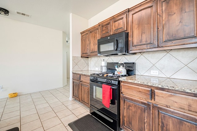 kitchen featuring decorative backsplash, light tile patterned floors, light stone countertops, and black appliances