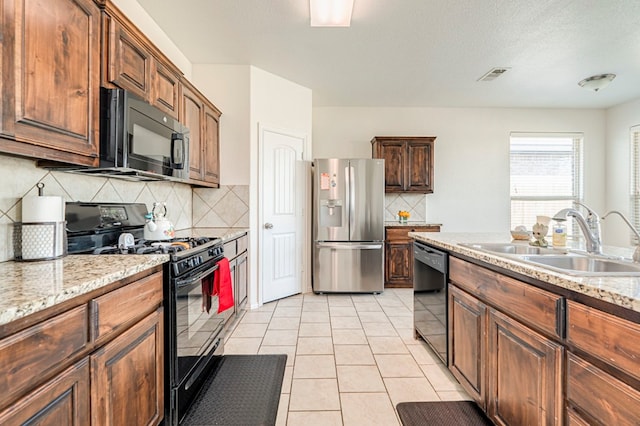 kitchen with tasteful backsplash, light stone countertops, sink, and black appliances