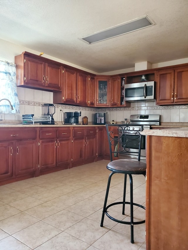 kitchen with light tile patterned floors, stainless steel appliances, sink, and backsplash