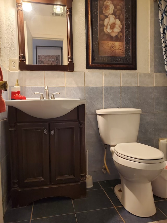 bathroom featuring vanity, toilet, tile patterned flooring, and tile walls