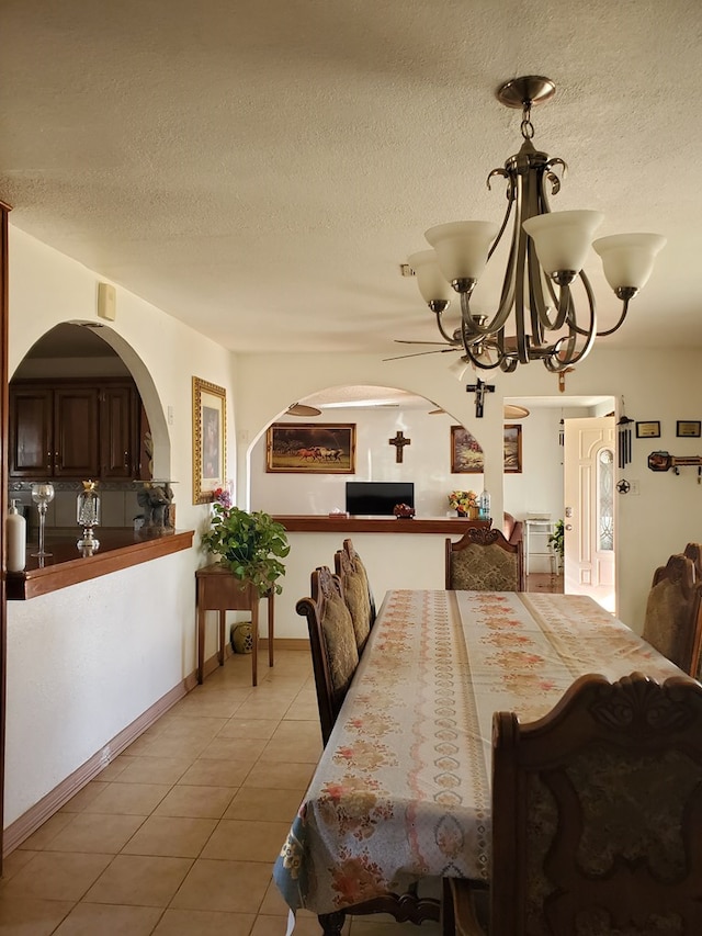 dining area featuring an inviting chandelier, a textured ceiling, and light tile patterned floors