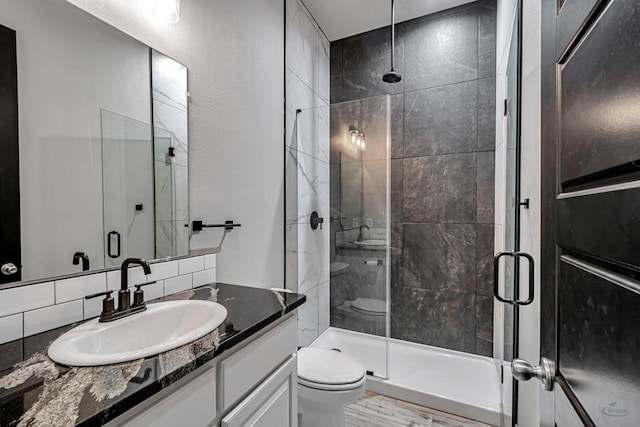 bathroom with a shower with door, vanity, backsplash, and toilet