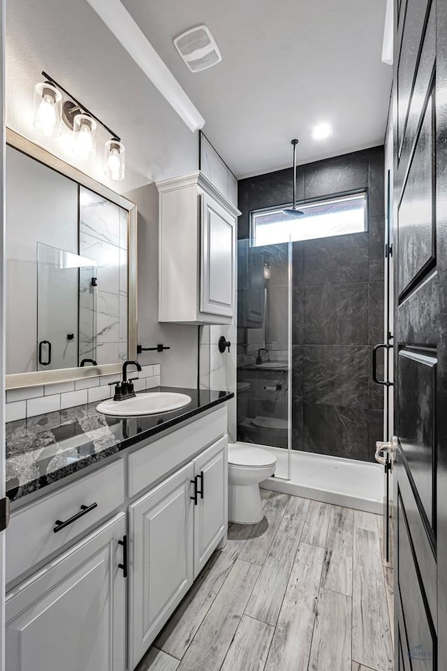 bathroom with a shower with door, vanity, wood-type flooring, and toilet