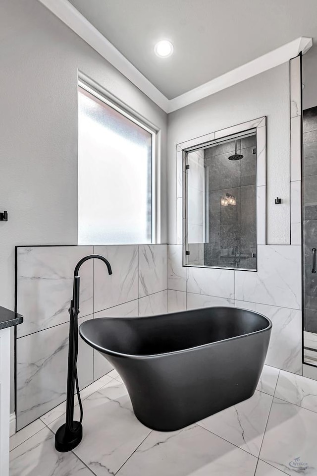 bathroom with ornamental molding, shower with separate bathtub, and tile walls