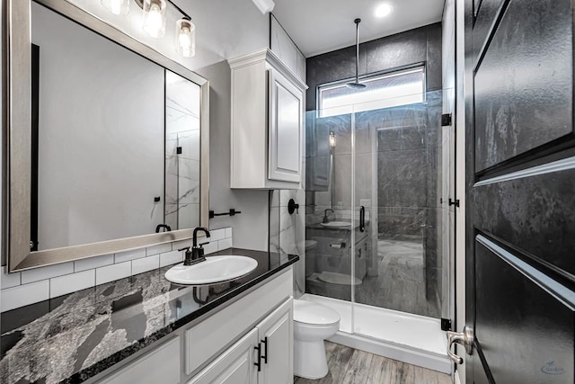 bathroom featuring hardwood / wood-style flooring, vanity, toilet, and a shower with door