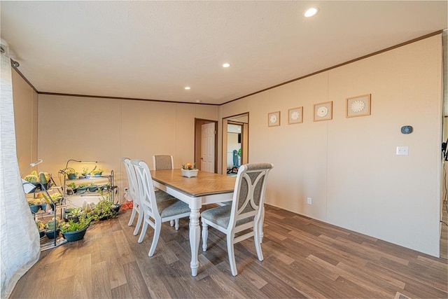 dining space featuring wood-type flooring and ornamental molding