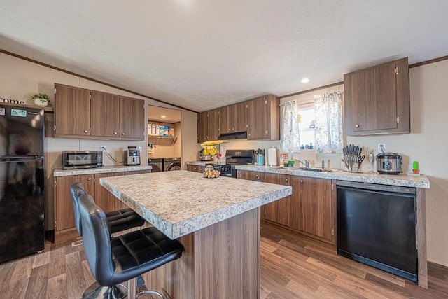 kitchen with a kitchen breakfast bar, sink, light hardwood / wood-style flooring, and black appliances