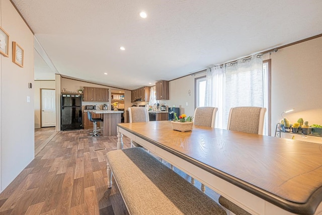 dining area featuring lofted ceiling, ornamental molding, and light wood-type flooring