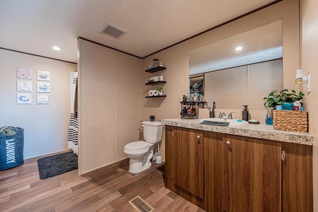 bathroom with vanity, wood-type flooring, ornamental molding, and toilet