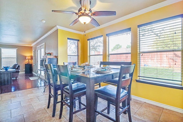 tiled dining space with plenty of natural light, ceiling fan, and crown molding