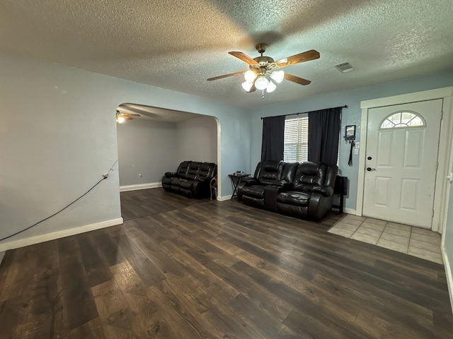 living room featuring a textured ceiling, dark hardwood / wood-style floors, and ceiling fan