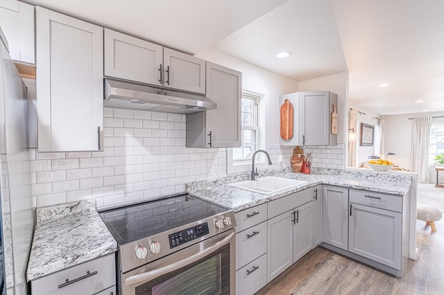 kitchen with gray cabinets, sink, electric range, light stone countertops, and light wood-type flooring