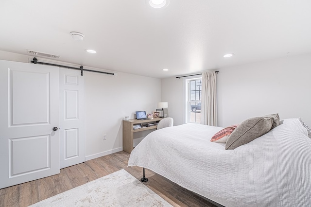 bedroom featuring a barn door and light hardwood / wood-style floors