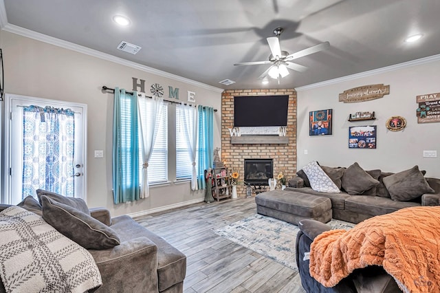 living room featuring ceiling fan, ornamental molding, light hardwood / wood-style floors, and a brick fireplace