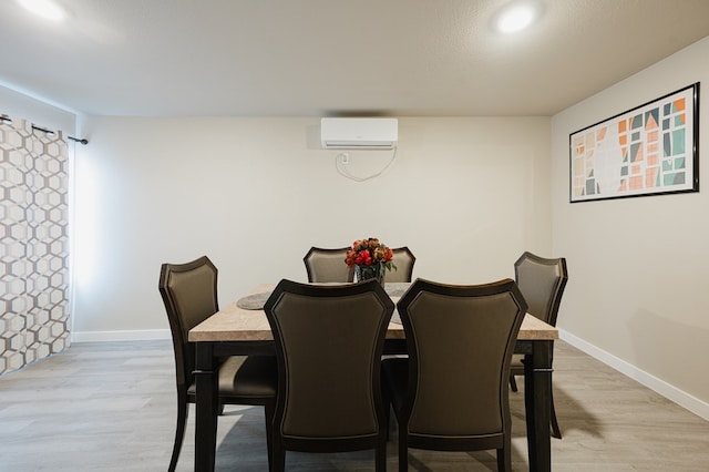 dining room with a wall mounted air conditioner and light hardwood / wood-style floors