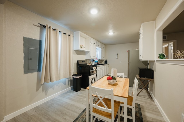 kitchen featuring light wood-type flooring, gas stove, sink, electric panel, and white cabinetry