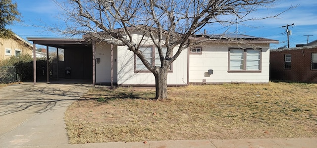 view of front of house featuring concrete driveway, a carport, solar panels, and a front yard