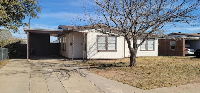 view of property exterior featuring a yard, fence, a carport, and concrete driveway