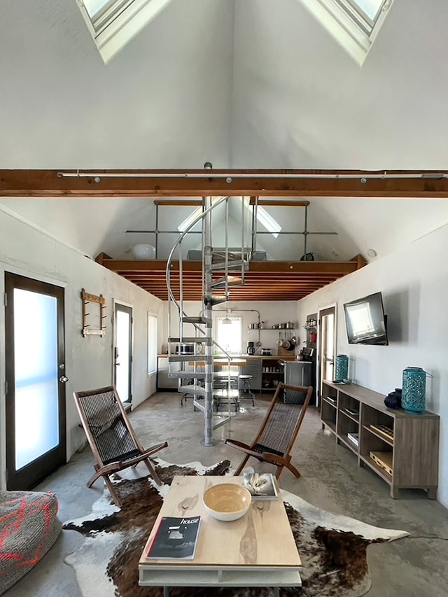 interior space featuring concrete flooring, a skylight, and high vaulted ceiling