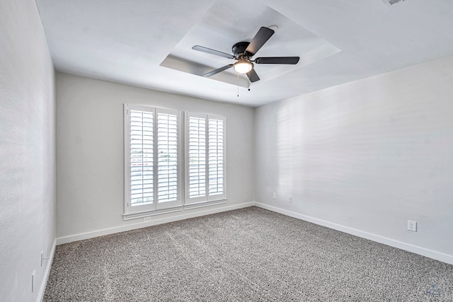 carpeted empty room featuring ceiling fan and a raised ceiling