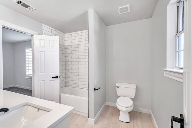 full bathroom with hardwood / wood-style floors, vanity, toilet, and tiled shower / bath