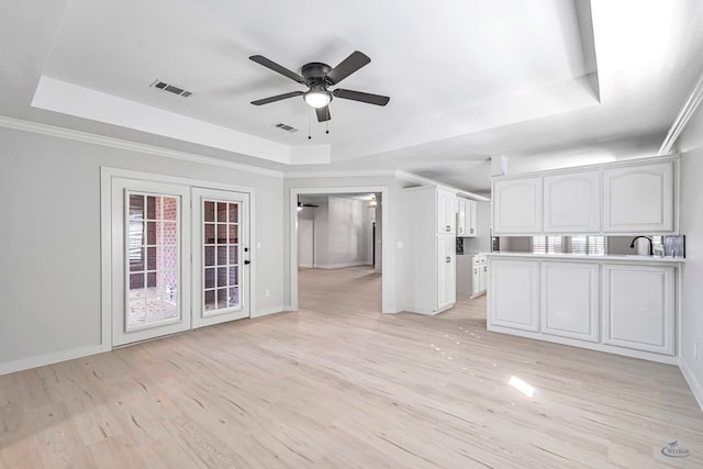 unfurnished living room featuring light hardwood / wood-style floors, a raised ceiling, ceiling fan, and sink