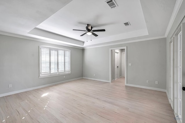 empty room with a raised ceiling, ceiling fan, light hardwood / wood-style flooring, and ornamental molding