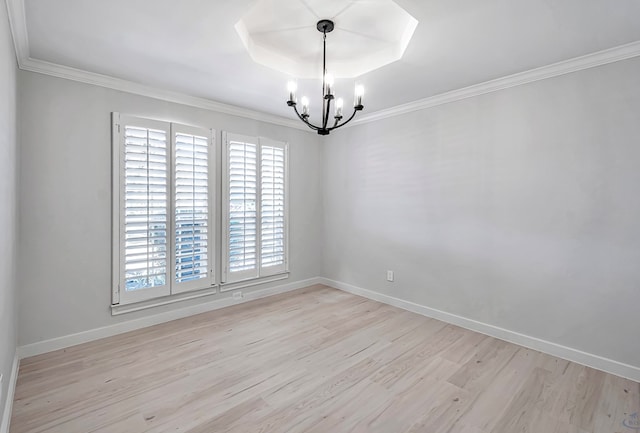 empty room with a chandelier, light hardwood / wood-style floors, a raised ceiling, and ornamental molding