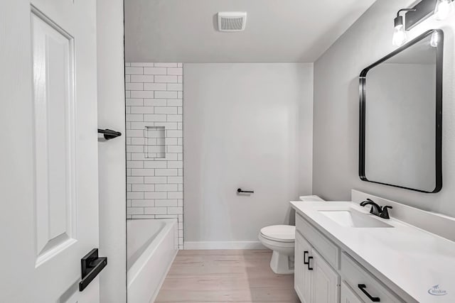 full bathroom featuring hardwood / wood-style floors, vanity, toilet, and tiled shower / bath combo