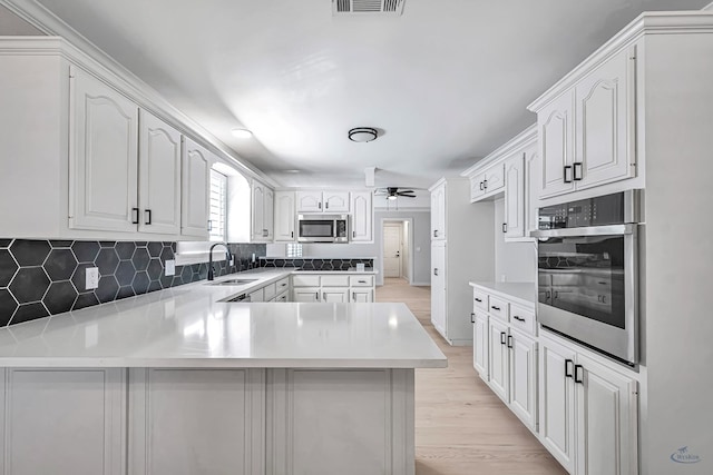 kitchen featuring kitchen peninsula, appliances with stainless steel finishes, white cabinetry, and sink