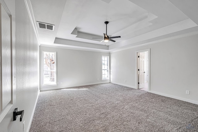 empty room featuring carpet floors, a raised ceiling, ceiling fan, and crown molding