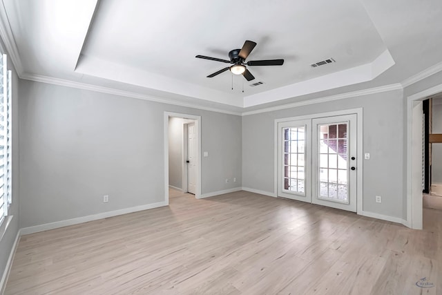 spare room with a raised ceiling, ceiling fan, and light hardwood / wood-style flooring