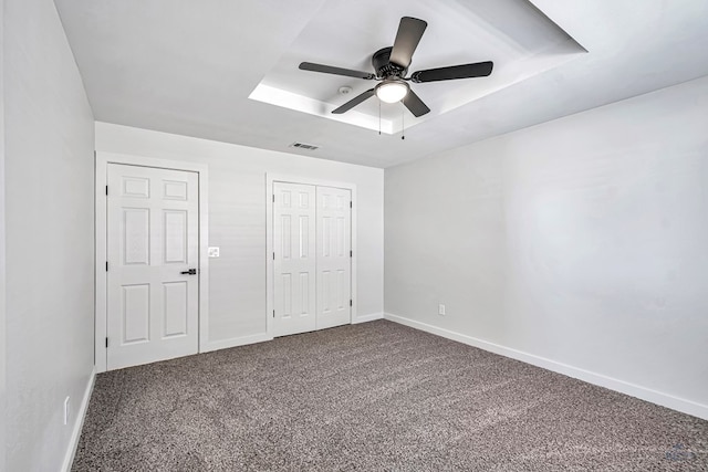 unfurnished bedroom featuring carpet, a tray ceiling, and ceiling fan