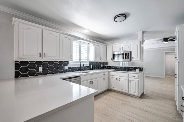 kitchen featuring sink, stainless steel appliances, backsplash, kitchen peninsula, and white cabinets