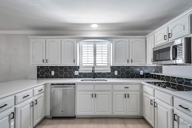 kitchen with decorative backsplash, white cabinetry, sink, and appliances with stainless steel finishes