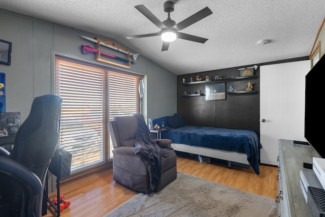 bedroom with vaulted ceiling, a textured ceiling, a ceiling fan, and wood finished floors