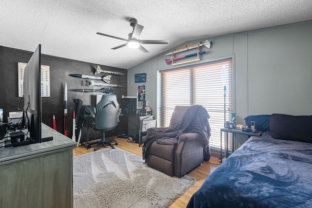 bedroom featuring a textured ceiling, vaulted ceiling, wood finished floors, and ceiling fan