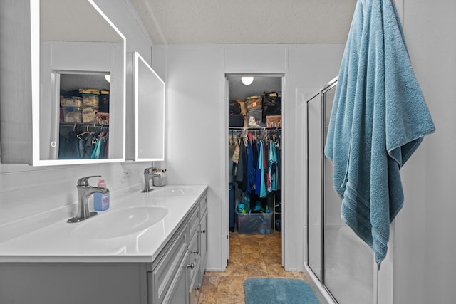 full bathroom featuring a sink, a stall shower, and double vanity