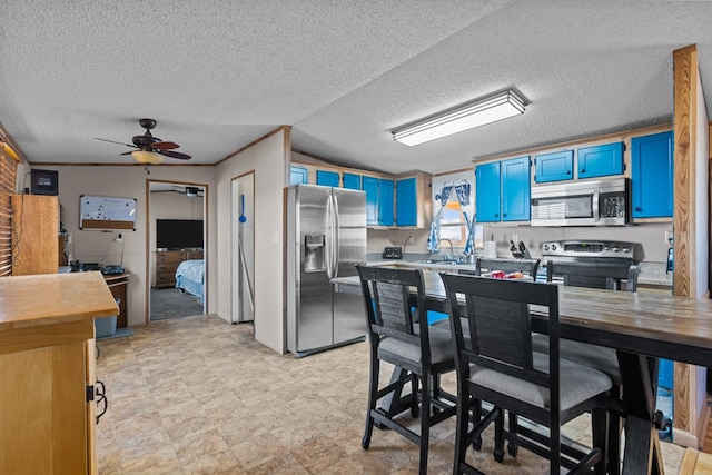 kitchen with blue cabinets, butcher block countertops, a ceiling fan, stainless steel appliances, and crown molding