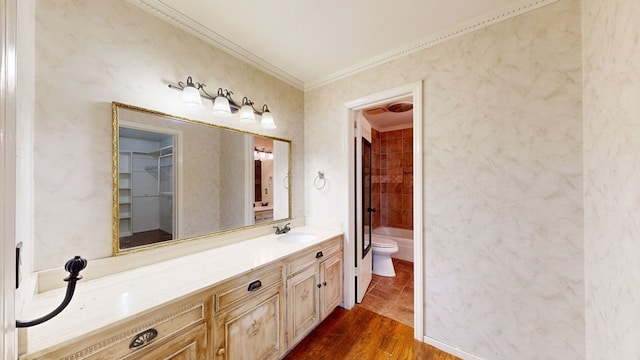 full bathroom featuring tiled shower / bath combo, vanity, crown molding, hardwood / wood-style floors, and toilet