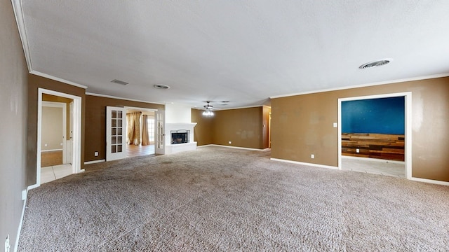 unfurnished living room featuring light carpet, ceiling fan, a textured ceiling, and ornamental molding