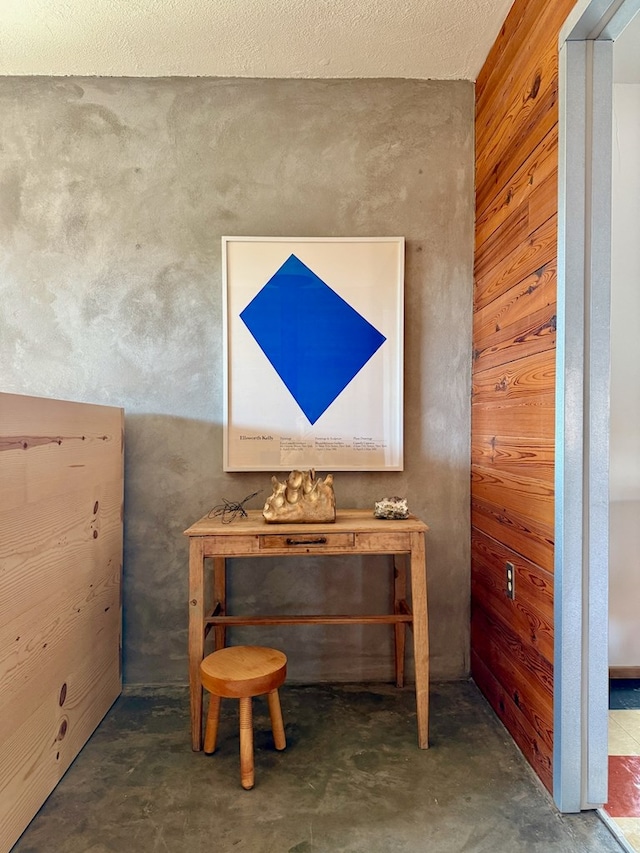 interior space with a textured ceiling and wood walls