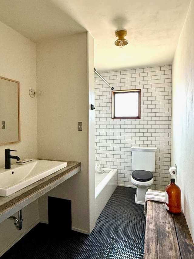 full bathroom featuring sink, tiled shower / bath combo, tile patterned flooring, toilet, and tile walls