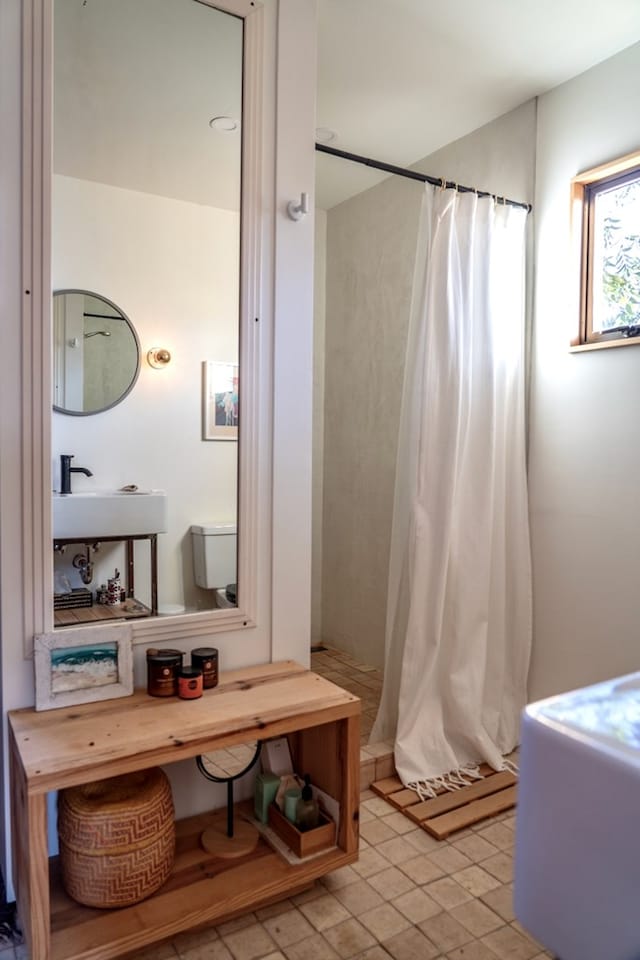 bathroom featuring a shower with curtain, sink, and toilet