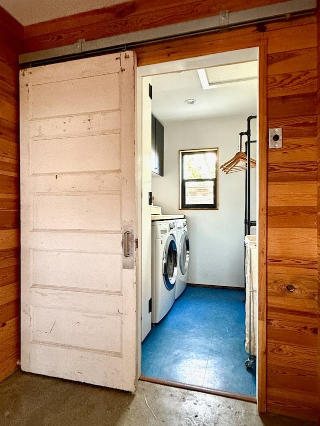 clothes washing area with wood walls and independent washer and dryer