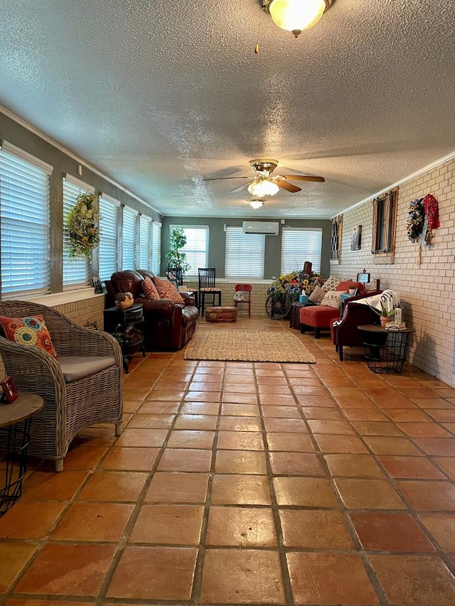 living room featuring ceiling fan, a wall mounted air conditioner, tile patterned flooring, brick wall, and a textured ceiling