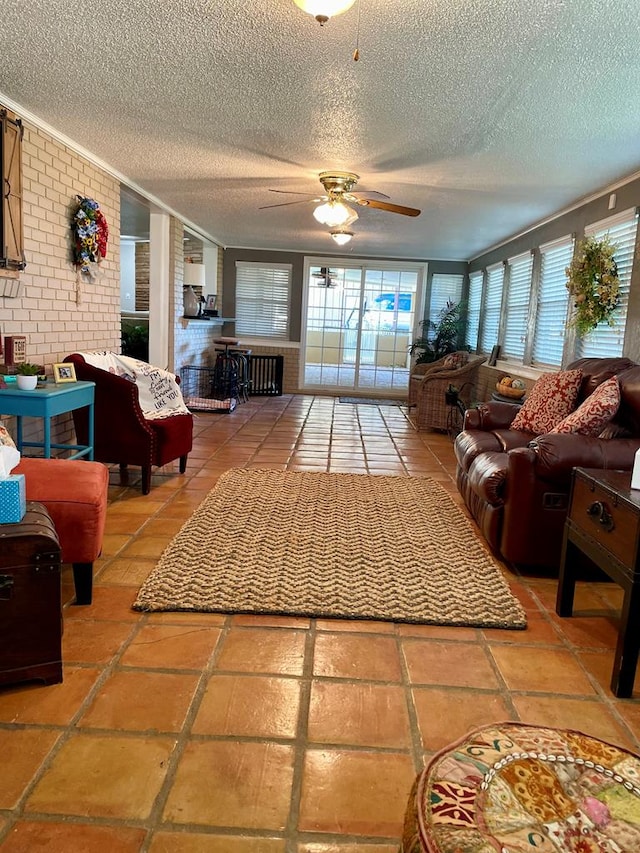 tiled living room featuring a textured ceiling, ceiling fan, and brick wall