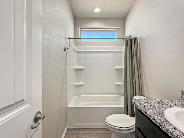 full bath with toilet, vanity, bathtub / shower combination, and a textured wall