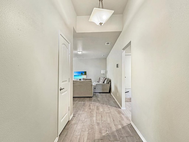 hallway with visible vents, baseboards, and wood finish floors